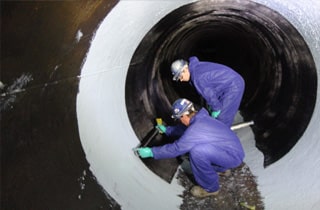 The interior of a pipeline being protected by two field services technicians installing HydraWrap