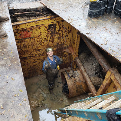 A Field Services Technician down near the entrance of the pipe