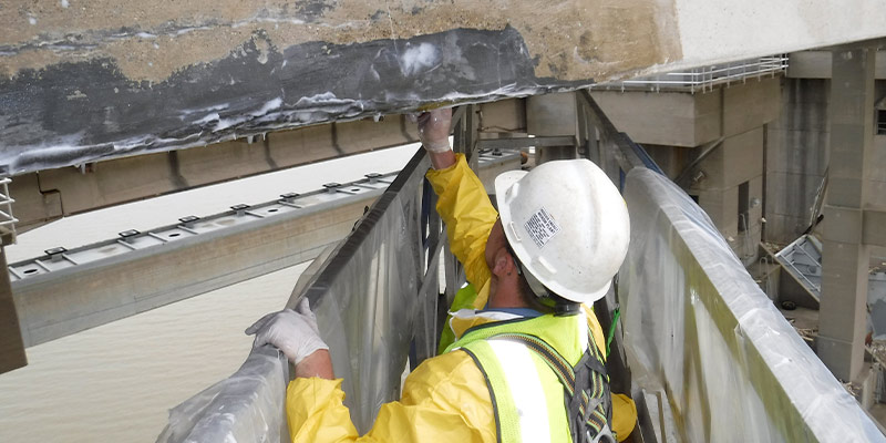 Field services technician applying epoxy on the underside of the markland bridge