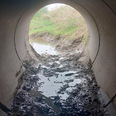 The invert of a culvert that is covered in loose debris