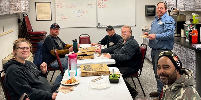 HydraTech employees sitting at a table eating pizza