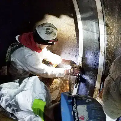 Two technicians installing HydraTite in a round pipe