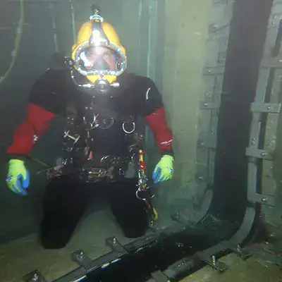 A Diver kneeling near a basin joint that is being sealed with HydraTite