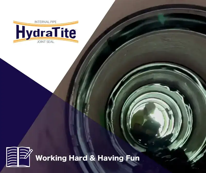 A technician sitting in a pipe that has had HydraTite installed over a joint, 'Working Hard & Having Fun'