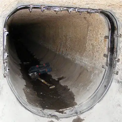 A technician sitting in a pipe with HydraTite seals installed over the pipe's joints