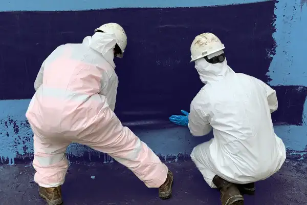 Two technicians applying HydraWrap to a concrete wall