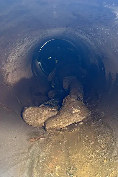 A technician in a small-diameter pipe installing HydraTite, the internal pipe joint seal, over a joint to fortify it against leaks