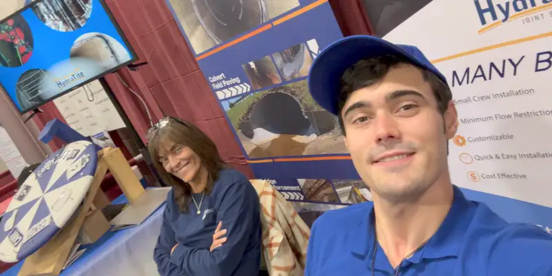 Two HydraTech Employees At A Booth A stack of steel on a shipping pallet
