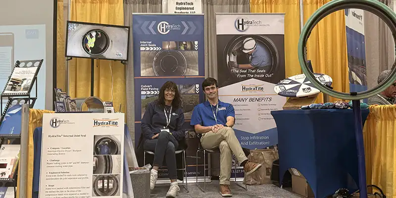 Two HydraTech Employees Sitting At A Tradeshow Booth two people sitting at a trade show booth