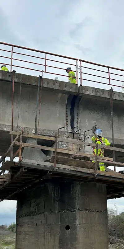 A few technicians near a failing exterior repair on a bridge