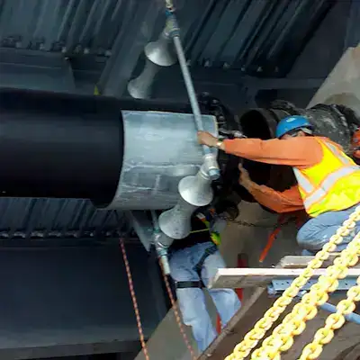 Two people pushing apart a pipe