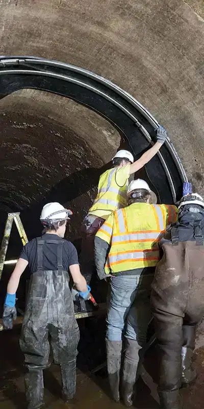 Several technicians positioning a large-diameter seal over a joint