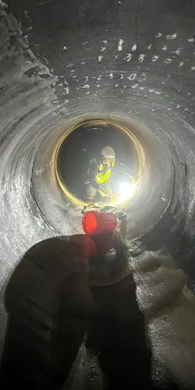 Technician inside a pipe preparing to repair a joint