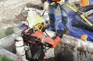 A diver lowering himself into a square culvert