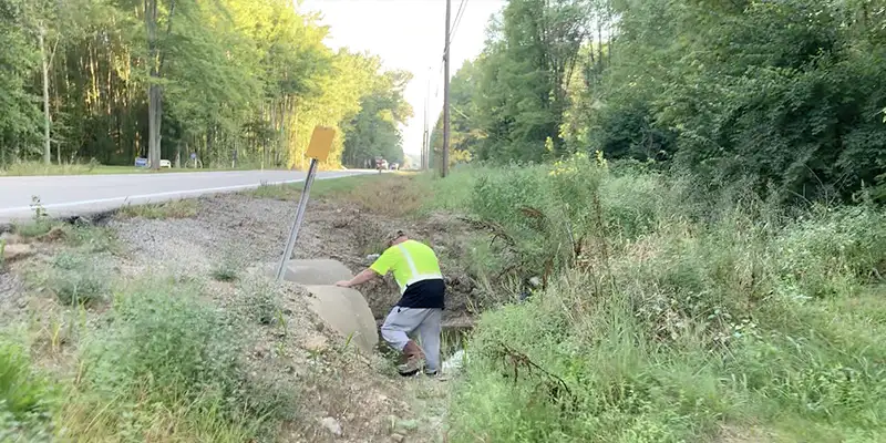 A technician looking into a stormwater culvert