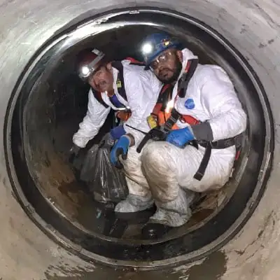 Two people sitting inside a pipe near a HydraTite Internal Pipe Joint Seal