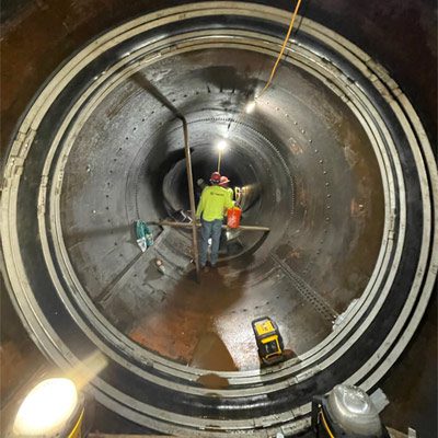 Technicians working inside a penstock pipe to restore its joints