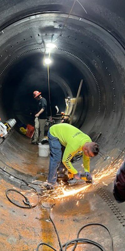 Technicians working inside a metal pipe sending sparks flying