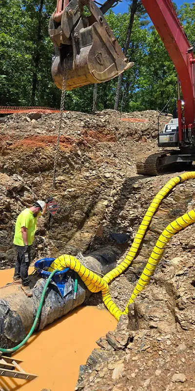 A technician standing above the opening to a drinking water pipe