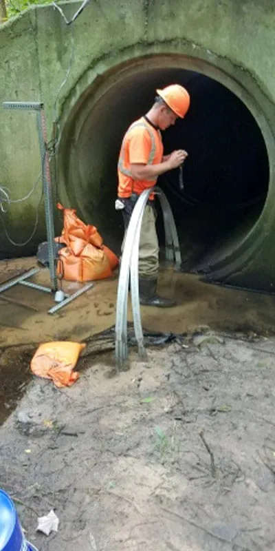 A technician standing near the entry of a pipe with several retaining bands