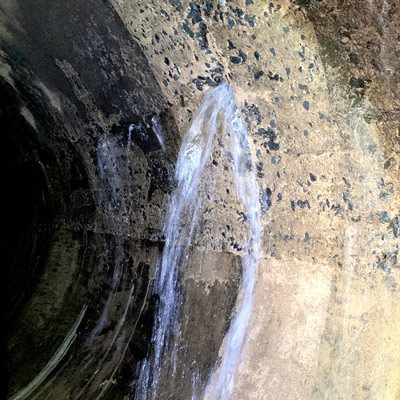 Water pouring into a pipe from the side of the pipe hrough a compromised point