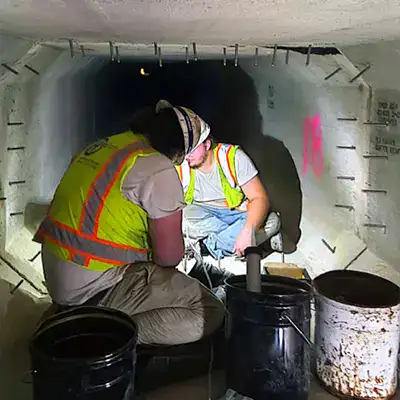 A long storm drain sump with anchors being put on either side of the joints