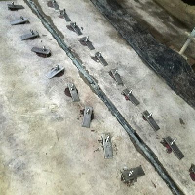 Anchors and hold-downs on both sides of an expansion joint