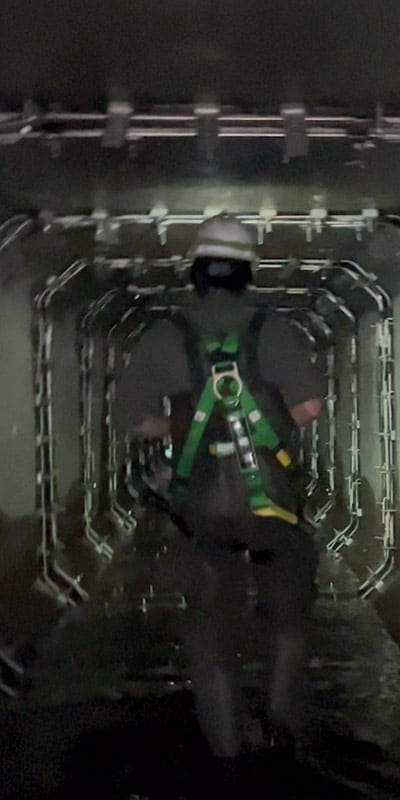 A technician walking through a box-shaped culvert