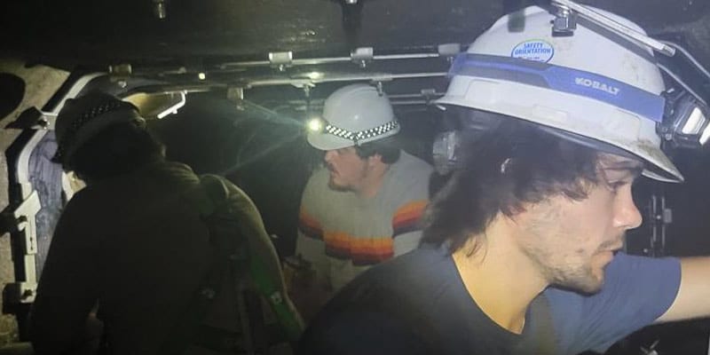 Technicians working inside a box-culvert, installing internal pipe joint seals over the joints
