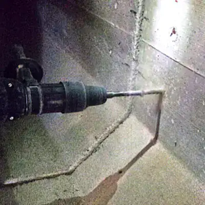 Holes being drilled on either side of a joint in a box-shaped storm drain sump
