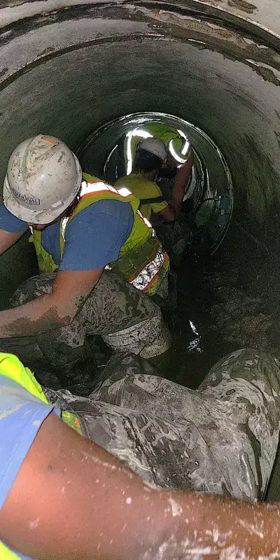 Technicians installing HydraTite over a joint in a culvert