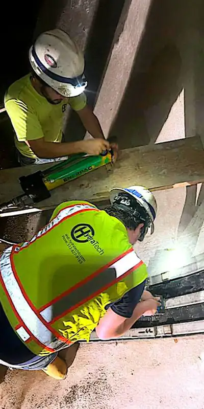 HydraTite being installed by two technicians in a large-diameter pipe to seal a joint