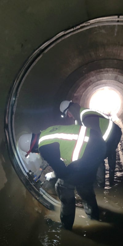 Technicians installing HydraTite over a joint in a pipe