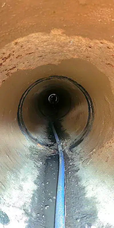 A long dark pipe where the tuberculation has been scrapped away from the interior wall near the pipe joint
