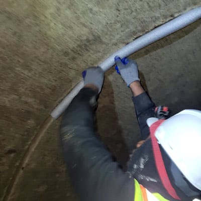 A field technician working foam filler into a pipe joint