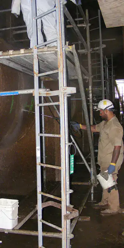 Two technicians working on the exterior of a large-diameter pipe