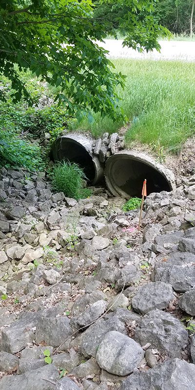 An elliptical-shaped concrete culvert entrance