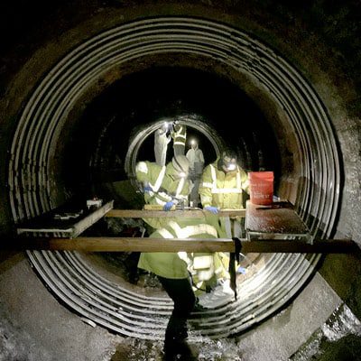 Technicians installing HydraTite over a joint in a large diameter pipe to ensure the joint is secure