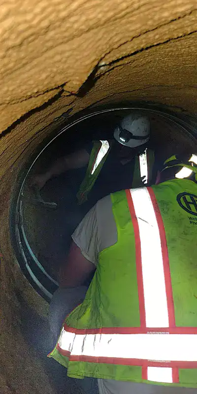 Technicians working inside a 48" pipeline to seal the joints with HydraTite