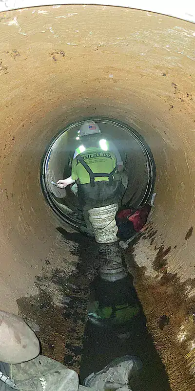 Technicians working inside a 48" pipeline to seal the joints with HydraTite