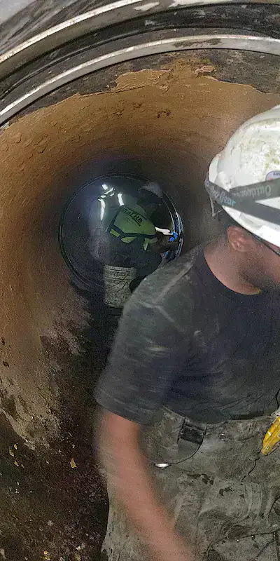 Technicians working inside a 48" pipeline to seal the joints with HydraTite