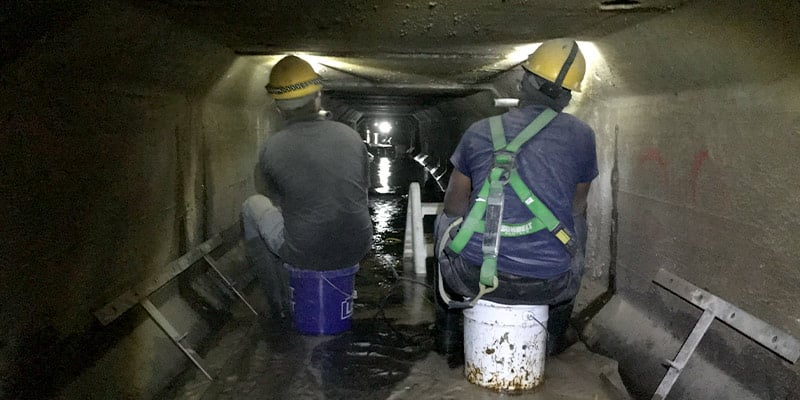 Several technicians sitting inside a box-culvert