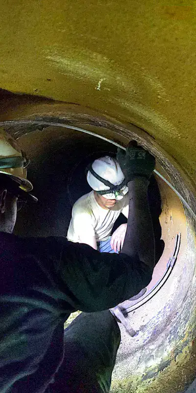 Technicians working inside a 48" pipeline to seal the joints with HydraTite