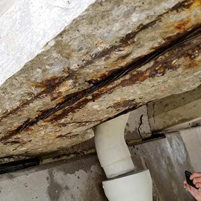 The underside of a bridge where deteriorated concrete has fallen away and exposed the rebar