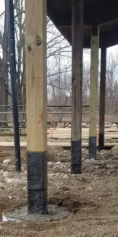 A row of wooden supports holding up a pavilion. The supports have been reinforced with HydraWrap