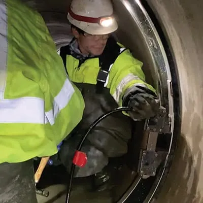 Two field technicians installing HydraTite over a joint with a hydraulic expander