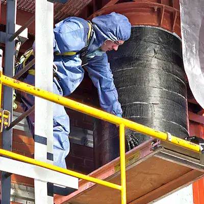 A technician applying a HydraWrap to the exterior of a vertical digester mixing pipe