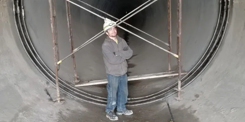A technician standing inside a large-diameter pipe near a HydraTite seal that has been installed over a joint