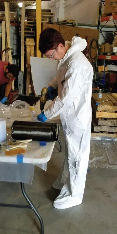 A woman in tyvek mixing epoxy on a table
