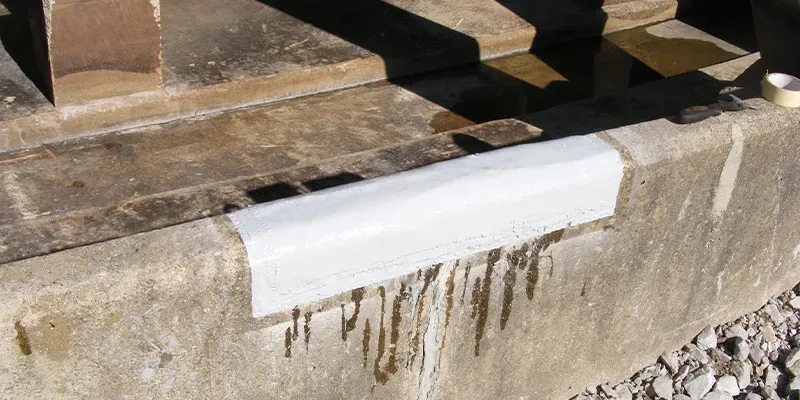 A crack running through a cooling tower basin's wall that has been restored with HydraWrap and top coated with a protective layer
